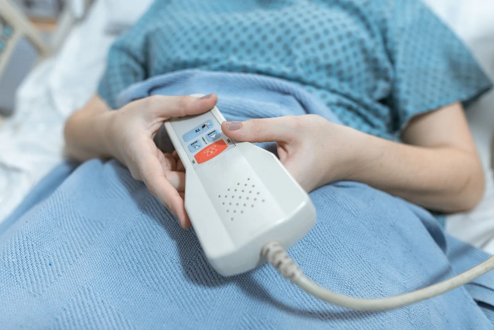 A resident holding a bedside call handset with a help button.