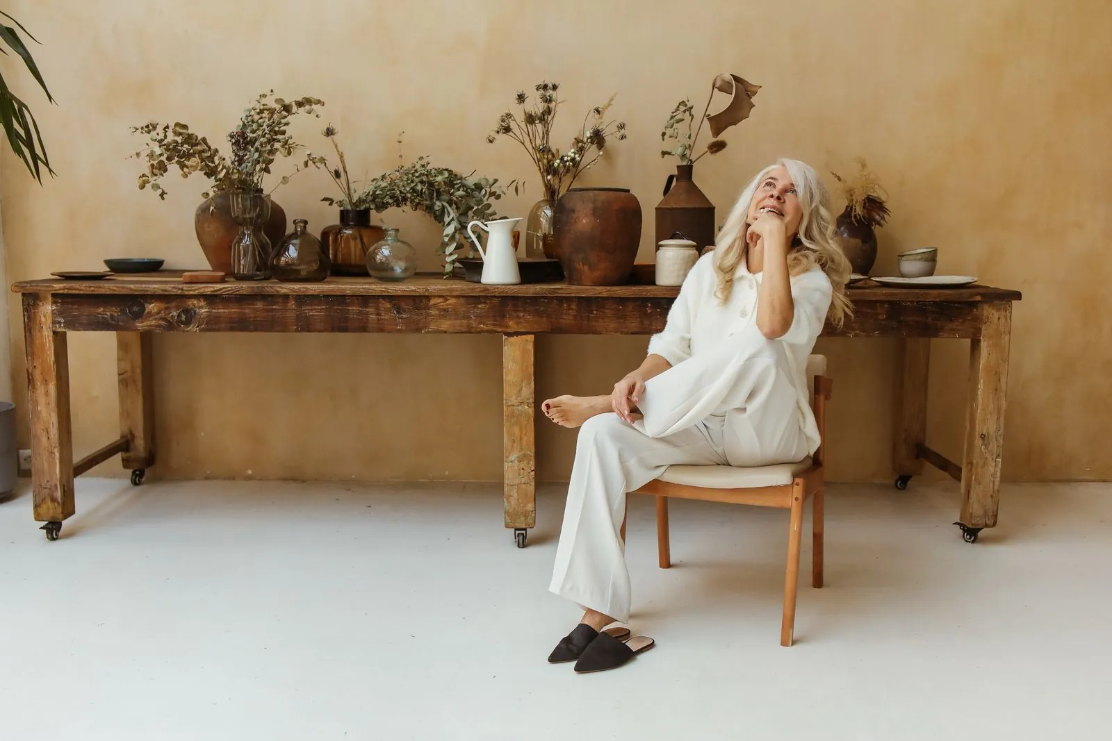 An older woman laughing and relaxed in a bright room.