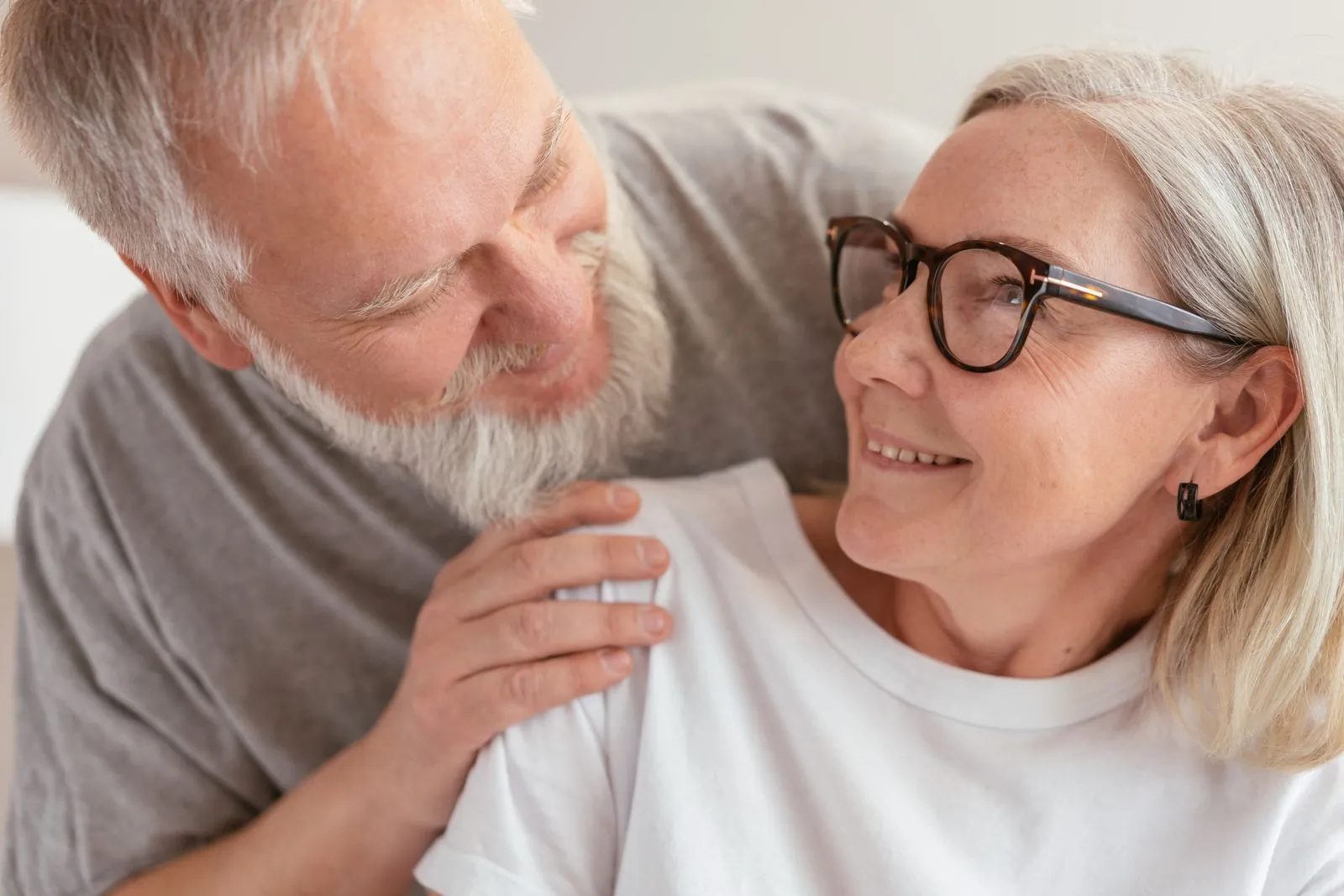 An older couple smiling at each other at home.