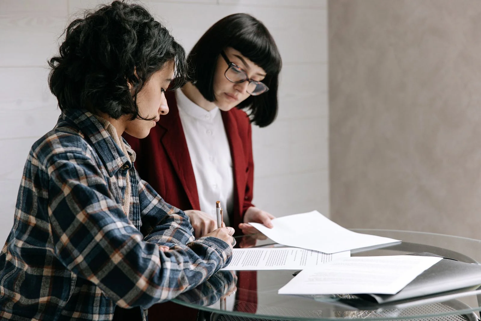 Two colleagues reviewing paper documents together at a table.