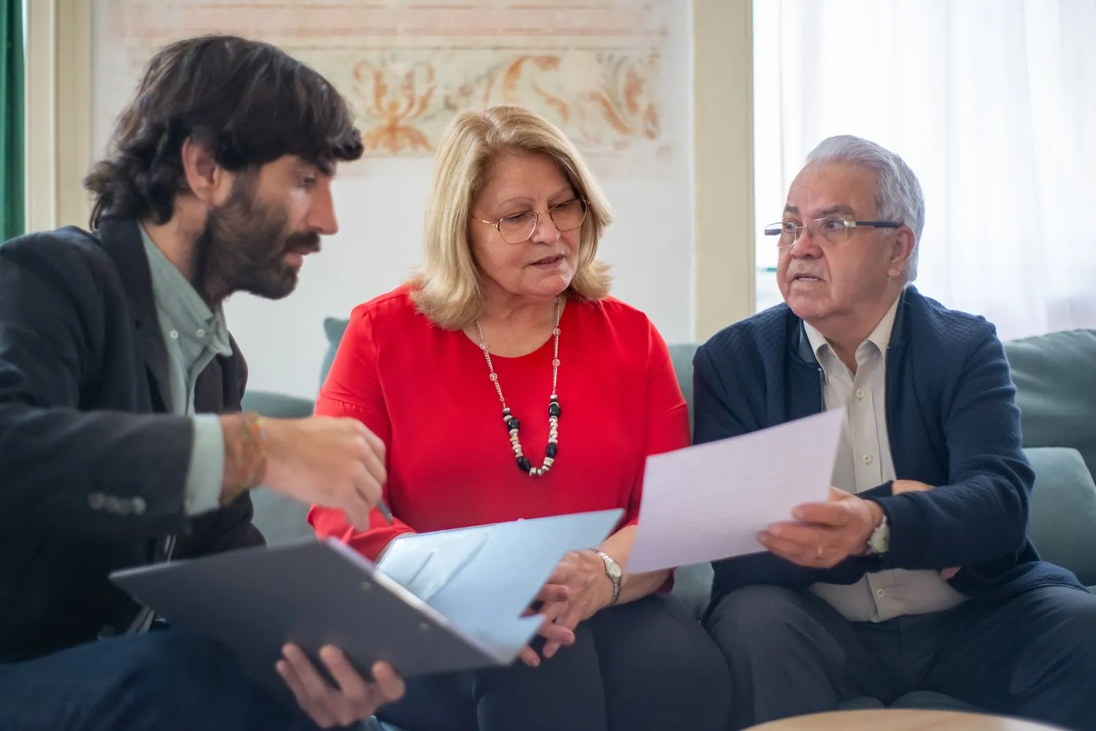 An older couple talking through paperwork with a member of staff.